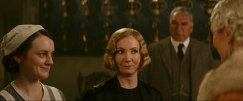 Movie still from “Downton Abbey: A New Era” (2022), directed by Simon Curtis – A woman with blonde hair wearing a black dress; Close Up shot, Over the shoulder angle