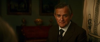 Movie still from “Downton Abbey: A New Era” (2022), directed by Simon Curtis – An older man wearing a suit and tie in a room; Close Up shot, Low angle