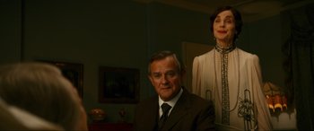 Movie still from “Downton Abbey: A New Era” (2022), directed by Simon Curtis – An older man in a suit sitting next to an older woman in a dress; Medium shot, Low angle