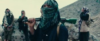 Movie still from “12 Strong” (2018), directed by Nicolai Fuglsig – A man with a rifle wearing a head covering; Medium shot, Low angle