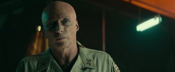 Movie still from “12 Strong” (2018), directed by Nicolai Fuglsig – A bald man in a military uniform looking at the camera; Close Up shot, Over the shoulder angle