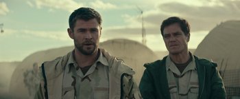 Movie still from “12 Strong” (2018), directed by Nicolai Fuglsig – Two men standing next to each other on a field; Medium shot, Over the shoulder angle