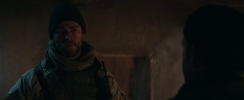 Movie still from “12 Strong” (2018), directed by Nicolai Fuglsig – A man wearing a jacket and a hat is looking at the camera; Close Up shot, Over the shoulder angle