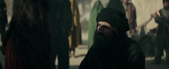Movie still from “12 Strong” (2018), directed by Nicolai Fuglsig – A man with a beard wearing a black turban; Medium shot, Over the shoulder angle