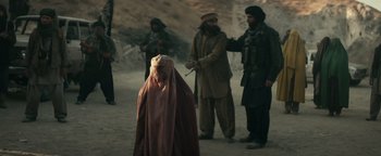 Movie still from “12 Strong” (2018), directed by Nicolai Fuglsig – A group of men standing next to each other on a dirt road; Wide shot, Over the shoulder angle