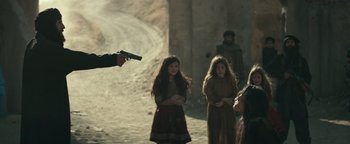 Movie still from “12 Strong” (2018), directed by Nicolai Fuglsig – A group of people standing next to each other on a dirt road; Medium shot, Over the shoulder angle