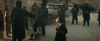 Movie still from “12 Strong” (2018), directed by Nicolai Fuglsig – A group of people standing on a dirt road near a white truck; Wide shot, Low angle