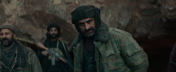 Movie still from “12 Strong” (2018), directed by Nicolai Fuglsig – A man with a beard wearing a hat and a jacket; Medium shot, Over the shoulder angle
