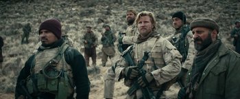 Movie still from “12 Strong” (2018), directed by Nicolai Fuglsig – A group of men standing on top of a hill; Medium shot, Over the shoulder angle