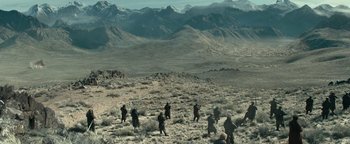 Movie still from “12 Strong” (2018), directed by Nicolai Fuglsig – A group of people walking across a desert plain; Extreme Wide shot, High angle