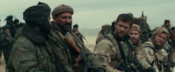 Movie still from “12 Strong” (2018), directed by Nicolai Fuglsig – Two men in military fatigues with guns in their hands; Medium shot, Over the shoulder angle