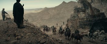 Movie still from “12 Strong” (2018), directed by Nicolai Fuglsig – A group of people riding horses down a mountain; Extreme Wide shot, High angle