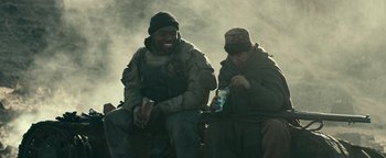 Movie still from “12 Strong” (2018), directed by Nicolai Fuglsig – Two people sitting on a bench eating some food; Medium shot, Over the shoulder angle