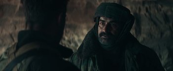 Movie still from “12 Strong” (2018), directed by Nicolai Fuglsig – A man with a beard wearing a hat and a jacket; Close Up shot, Over the shoulder angle