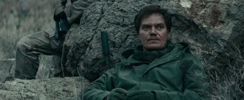 Movie still from “12 Strong” (2018), directed by Nicolai Fuglsig – A man sitting on top of a rock near some rocks; Close Up shot, Low angle