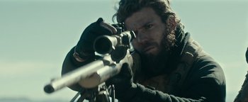 Movie still from “12 Strong” (2018), directed by Nicolai Fuglsig – A man with a beard is holding a rifle; Close Up shot, Over the shoulder angle