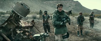 Movie still from “12 Strong” (2018), directed by Nicolai Fuglsig – A group of men standing next to each other in the desert; Medium shot, Over the shoulder angle