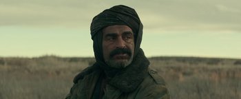 Movie still from “12 Strong” (2018), directed by Nicolai Fuglsig – A man with a beard wearing a turban and a jacket; Close Up shot, Over the shoulder angle