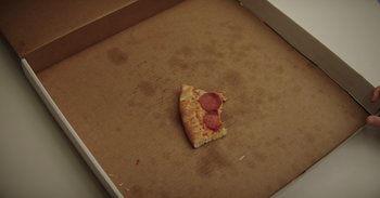 Movie still from “Dramarama” (2020), directed by Jonathan Wysocki – A piece of pizza sitting on top of a cardboard box; Extreme Close Up shot, High angle