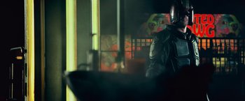 Movie still from “Dredd” (2012), directed by Pete Travis – A man in a black leather jacket standing next to a window; Medium shot, Low angle