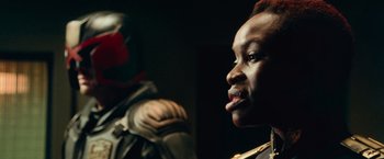 Movie still from “Dredd” (2012), directed by Pete Travis – A man in a military uniform is looking into the distance; Close Up shot, Over the shoulder angle