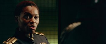 Movie still from “Dredd” (2012), directed by Pete Travis – A woman in a uniform is standing in front of a mirror; Close Up shot, Over the shoulder angle