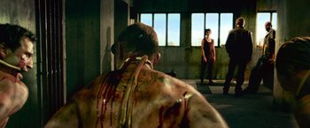 Movie still from “Dredd” (2012), directed by Pete Travis – A man with blood all over his face and back of his head; Wide shot, Over the shoulder angle