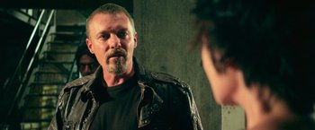 Movie still from “Dredd” (2012), directed by Pete Travis – A man in a leather jacket looking at himself in a mirror; Close Up shot, Over the shoulder angle