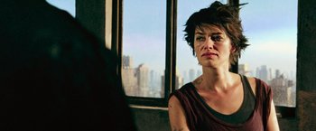 Movie still from “Dredd” (2012), directed by Pete Travis – A woman in a red shirt is looking out of a window; Close Up shot, Over the shoulder angle