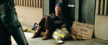 Movie still from “Dredd” (2012), directed by Pete Travis – A man sitting on the ground next to a bag of food; Wide shot, Low angle