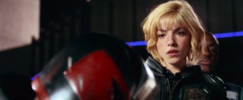Movie still from “Dredd” (2012), directed by Pete Travis – A woman in a black jacket is looking at a helmet; Close Up shot, Over the shoulder angle