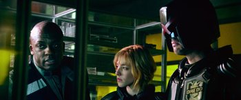Movie still from “Dredd” (2012), directed by Pete Travis – A woman is standing on a bus holding a brush; Close Up shot, Low angle