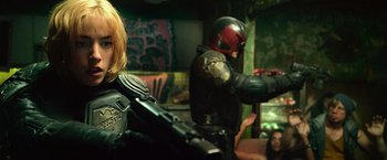 Movie still from “Dredd” (2012), directed by Pete Travis – A man in a motorcycle suit and a woman in a motorcycle suit; Medium shot, Over the shoulder angle