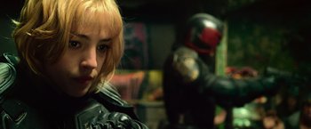 Movie still from “Dredd” (2012), directed by Pete Travis – A woman with blonde hair wearing a black leather jacket; Close Up shot, Over the shoulder angle
