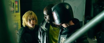 Movie still from “Dredd” (2012), directed by Pete Travis – Two men and a woman in leather jackets and a helmet; Medium shot, Over the shoulder angle