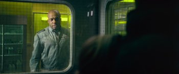Movie still from “Dredd” (2012), directed by Pete Travis – A man looking out of a window on a train; Medium shot, Over the shoulder angle