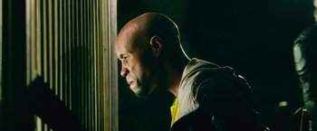 Movie still from “Dredd” (2012), directed by Pete Travis – A bald man looking out of a window at night; Close Up shot, Low angle