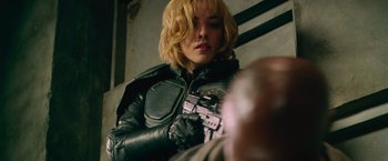 Movie still from “Dredd” (2012), directed by Pete Travis – A woman in a black leather jacket holding a gun; Close Up shot, Over the shoulder angle