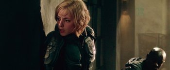 Movie still from “Dredd” (2012), directed by Pete Travis – A woman with blonde hair wearing a green jacket; Close Up shot, Over the shoulder angle