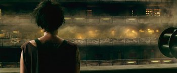 Movie still from “Dredd” (2012), directed by Pete Travis – A person standing in front of an industrial building; Medium shot, High angle