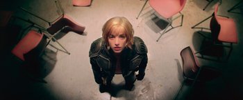 Movie still from “Dredd” (2012), directed by Pete Travis – A woman in a leather jacket standing on the ground; Medium shot, Overhead angle