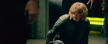 Movie still from “Dredd” (2012), directed by Pete Travis – A woman with blond hair wearing a motorcycle suit; Medium shot, Over the shoulder angle
