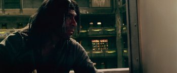 Movie still from “Dredd” (2012), directed by Pete Travis – A man in a room with a lot of shelves in the background; Medium shot, Low angle