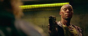 Movie still from “Dredd” (2012), directed by Pete Travis – A man holding a camera in front of a yellow light; Close Up shot, Low angle