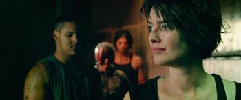 Movie still from “Dredd” (2012), directed by Pete Travis – A group of people standing in a dark room; Close Up shot, Over the shoulder angle