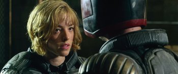 Movie still from “Dredd” (2012), directed by Pete Travis – A woman looking at a man with a helmet on; Close Up shot, Over the shoulder angle
