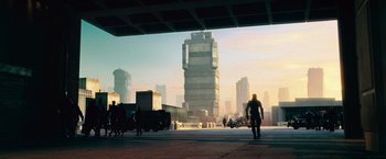 Movie still from “Dredd” (2012), directed by Pete Travis – A man riding a motorcycle down a street next to tall buildings; Extreme Wide shot, Low angle