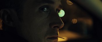 Movie still from “Drive” (2011), directed by Nicolas Winding Refn – A man's face with a green light shining on him; Extreme Close Up shot, Low angle