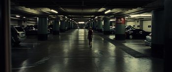 Movie still from “Drive” (2011), directed by Nicolas Winding Refn – A person walking in a parking garage with cars parked in the background; Extreme Wide shot, High angle