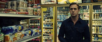 Movie still from “Drive” (2011), directed by Nicolas Winding Refn – A man standing in front of a display case of beer; Medium shot, Over the shoulder angle